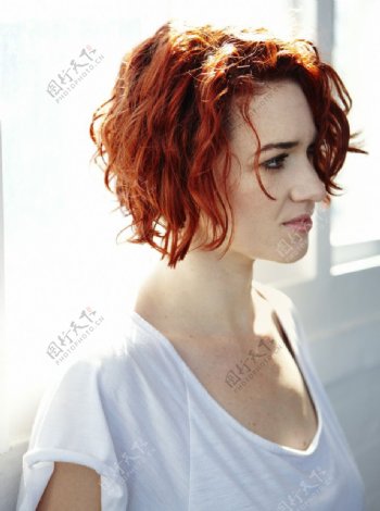 靠在窗边的红头发美女图片