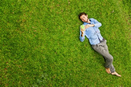 躺在草地上耍手机的男性图片