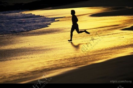 傍晚在沙滩跑步的男子图片