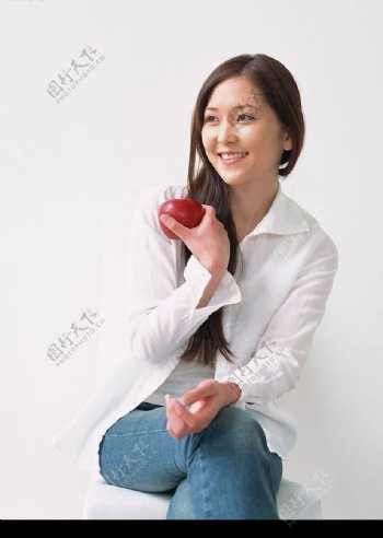 坐在凳子上拿着苹果微笑的美女图片