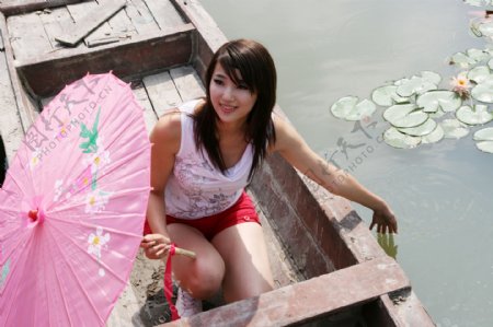 小木船上戴着伞的美女图片