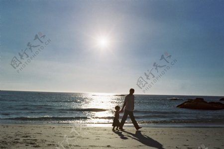 沙滩上散步的父子图片