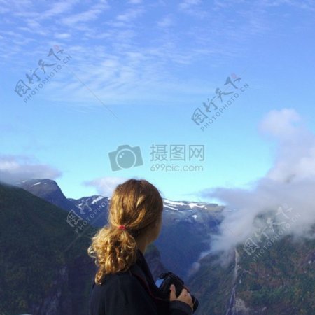 女人穿着黑色长袖衬衫白天上白下绿和布朗山和蓝天观看