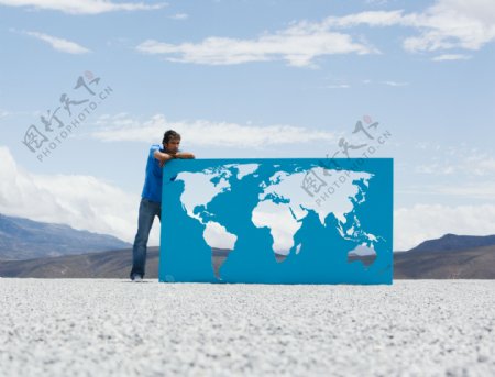 外国男人扶在镂空世界地图上图片