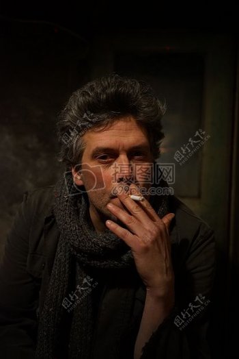 男子在黑色外套配灰色针织围巾吸烟