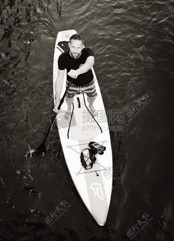 男子站在冲浪板水赛艇在灰度摄影