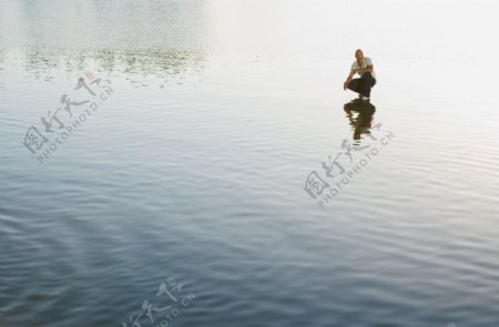 远处蹲在水面上的男人图片
