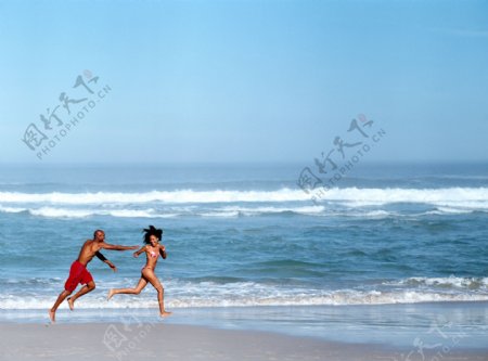 沙滩上奔跑玩耍的男女图片