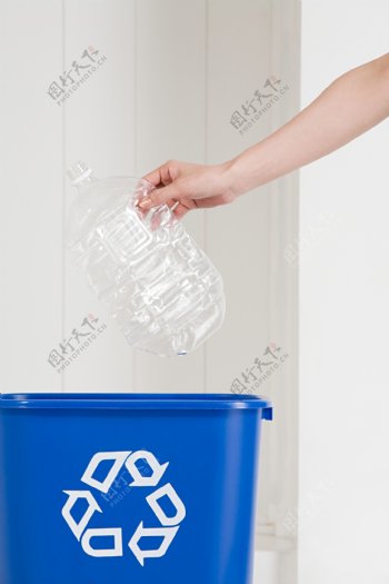手拿塑料瓶子丢入垃圾桶图片