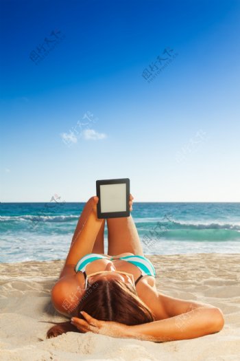 睡在海滩上玩平板电脑的美女图片