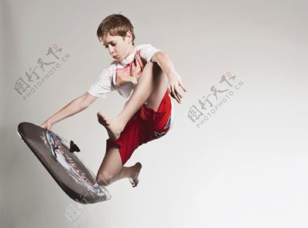 手拿冲浪板跳跃的外国男孩图片
