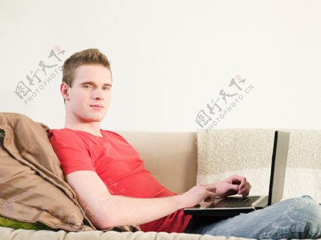 外国男人躺在沙发上玩电脑图片