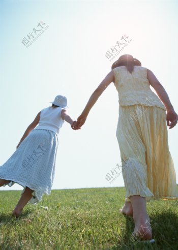 手牵手行走在草地上的女人图片