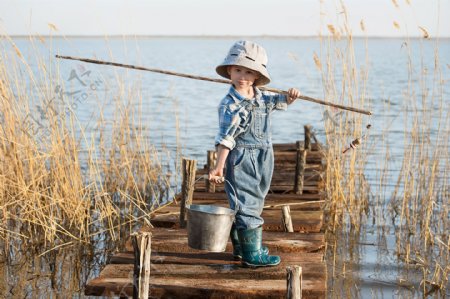 湖边提桶钓鱼的小男孩
