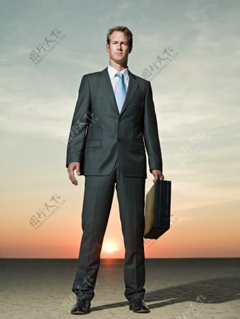 夕阳下提着皮包的高大外国男人图片