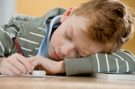 教室里趴着课桌上写字的小男孩图片