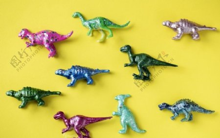 黄色表面上的五颜六色的玩具恐龙